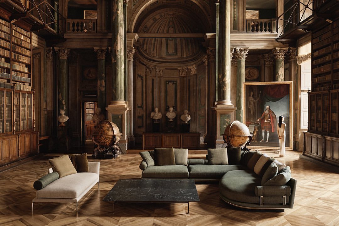 Opulent library interior featuring a sage sectional sofa, chaise lounge, marble coffee table, and globes, illuminated by natural light.