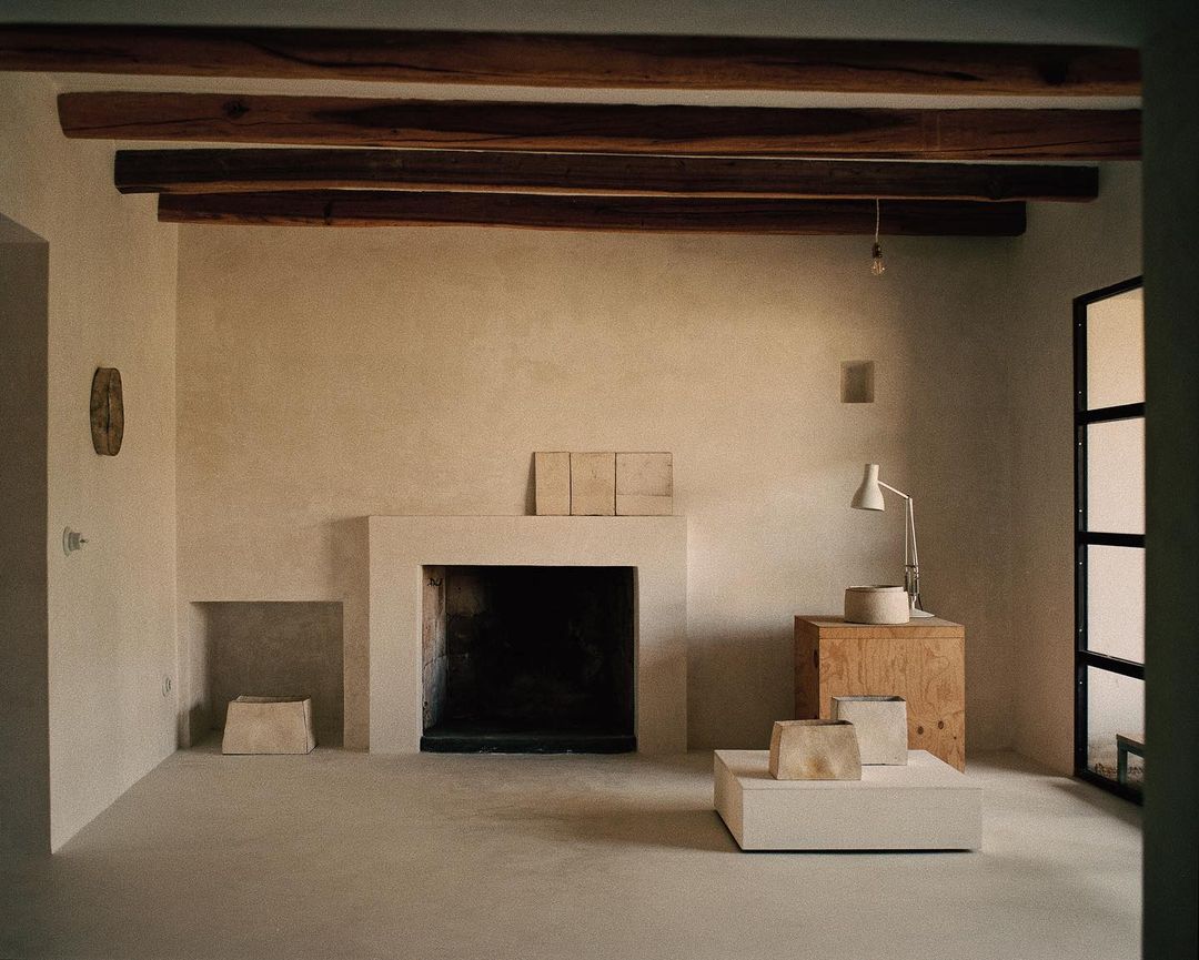 Minimalist interior featuring a modern fireplace, wooden beams, and neutral color palette, creating a serene and contemporary living space.