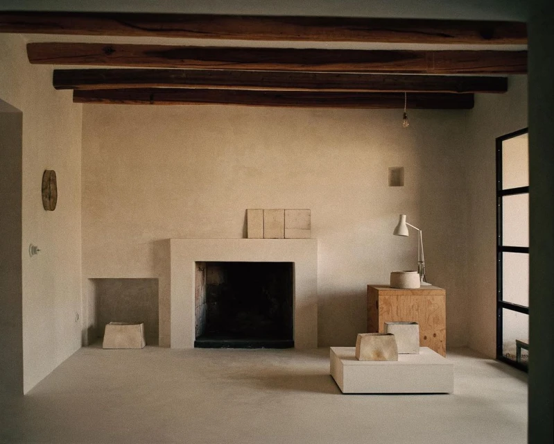 Minimalist interior featuring a modern fireplace, wooden beams, and neutral color palette, creating a serene and contemporary living space.