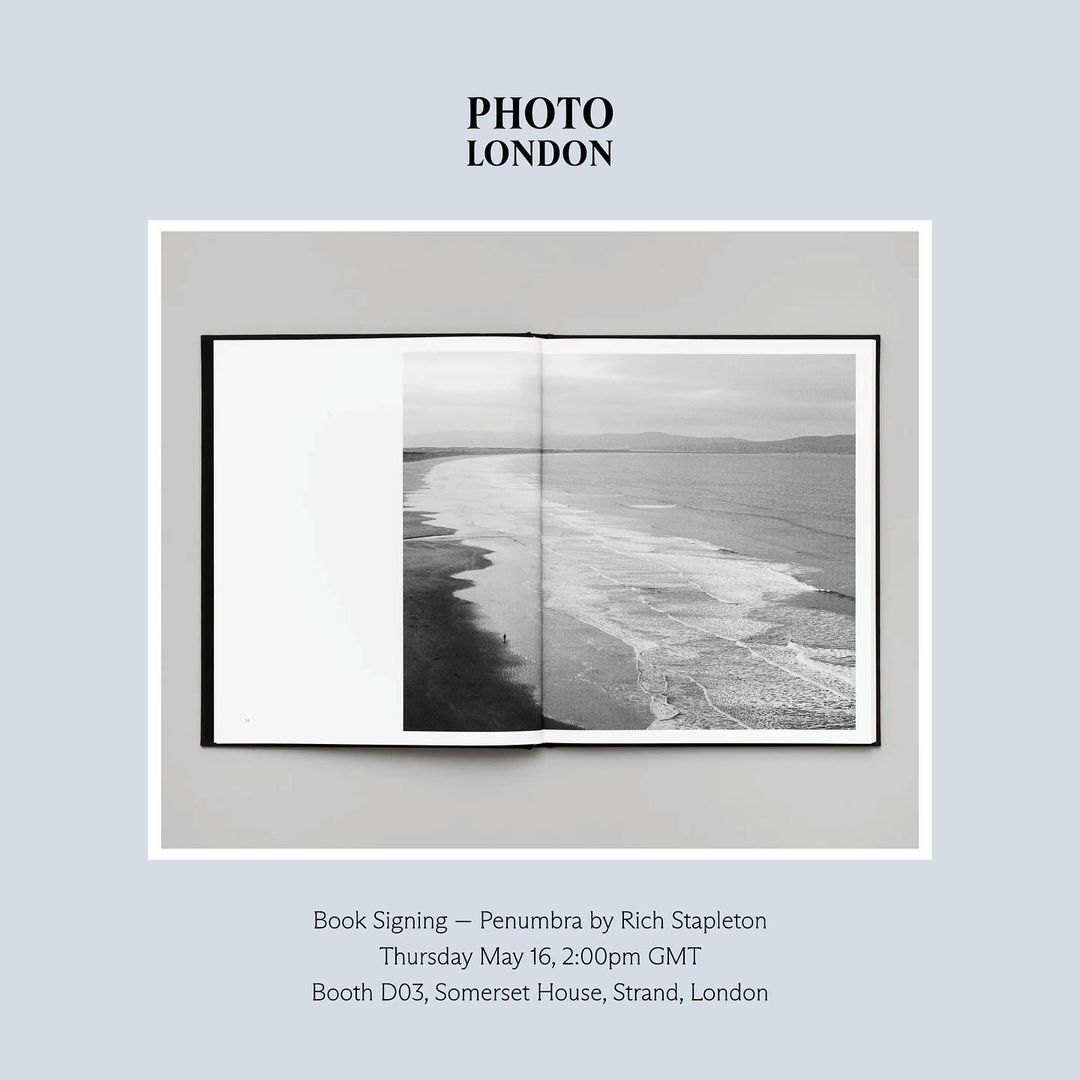 An open photography book displaying a black and white coastal landscape photograph set against a pale background.