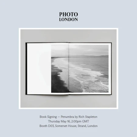 An open photography book displaying a black and white coastal landscape photograph set against a pale background.