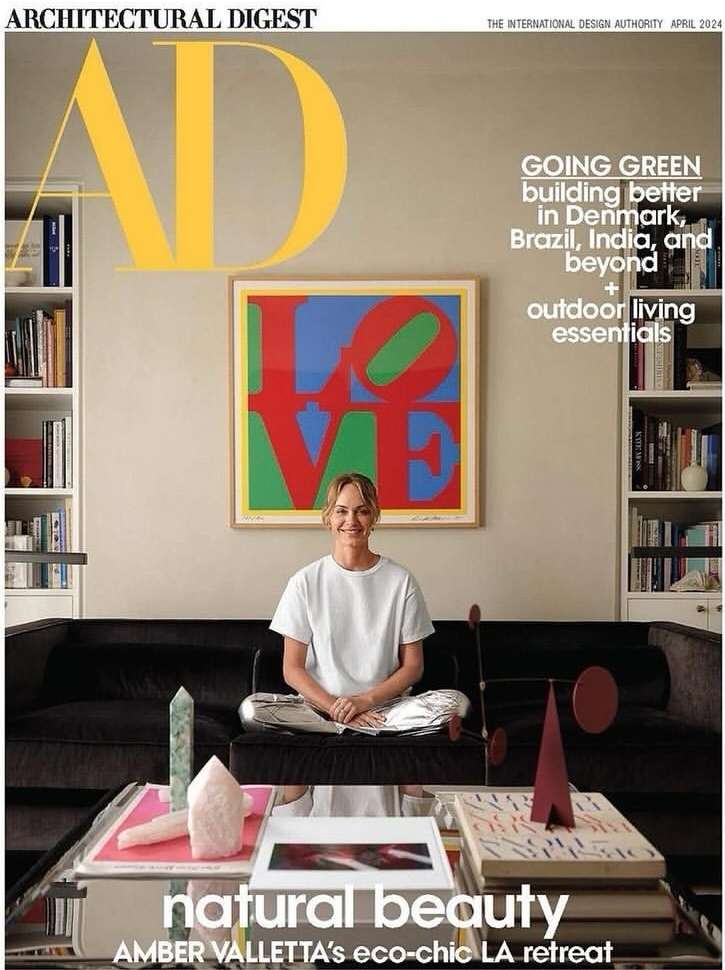 Architectural Digest cover featuring Amber Valletta in eco-chic LA home interior with art, coffee table objects, and bookshelves.