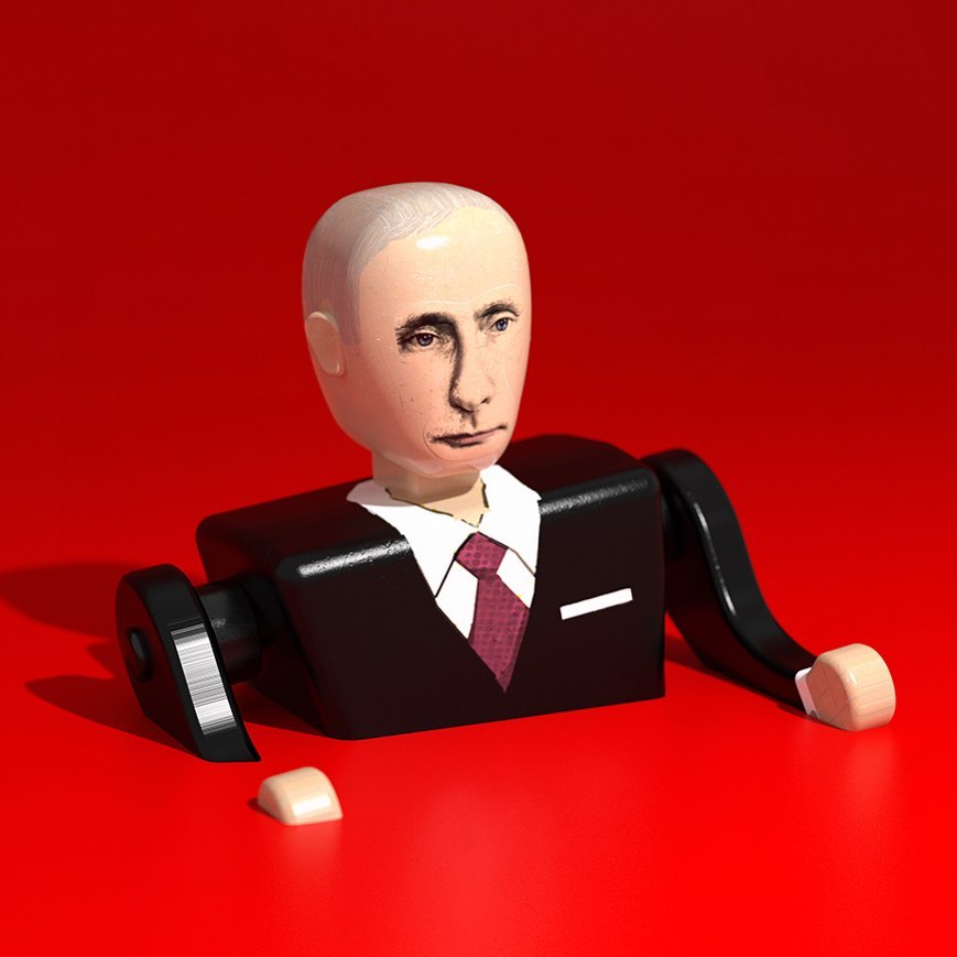 Wooden figure of a man in a suit with a painted face on a red surface, shot in a photo studio with bright lighting.