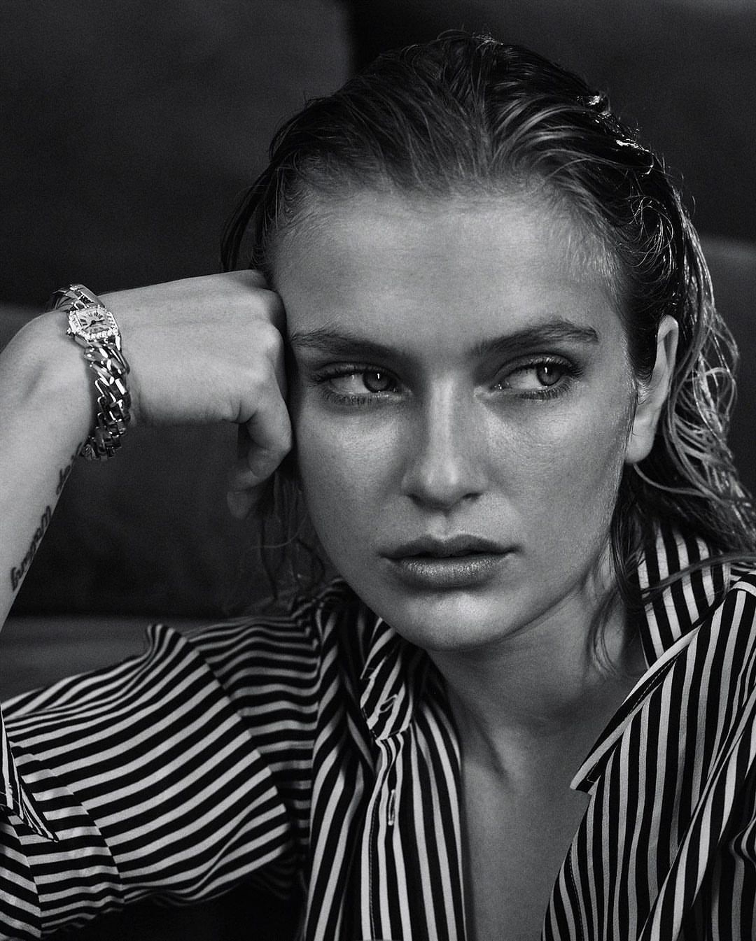 Black and white portrait of an adult woman with wet hair, wearing a striped shirt, and a chain bracelet, looking off-camera.