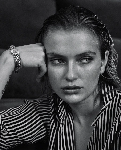 Black and white portrait of an adult woman with wet hair, wearing a striped shirt, and a chain bracelet, looking off-camera.