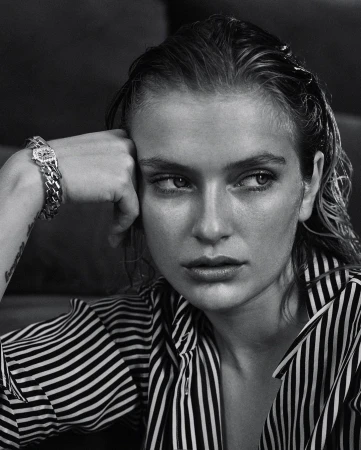 Black and white portrait of an adult woman with wet hair, wearing a striped shirt, and a chain bracelet, looking off-camera.
