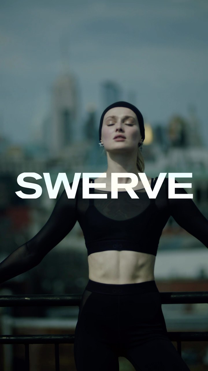 An adult female in black athletic wear stands in front of a cityscape with her arms outstretched and the word "SWERVE" overlaid.