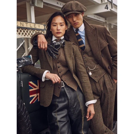 An Asian man and woman in vintage clothing, leaning against a car with a Union Jack, showcasing classic fashion in an outdoor setting.