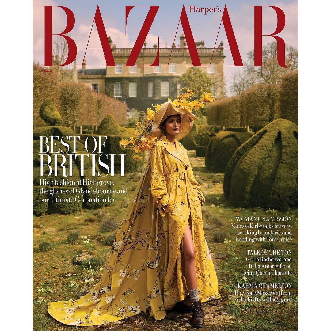 Harper's Bazaar magazine cover featuring a woman in a yellow floral trench coat and hat standing in a garden with a mansion backdrop.