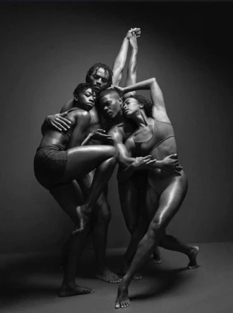 Monochrome art photo showcasing a group of four athletic African-descent dancers intertwined in a dynamic performance pose in studio.