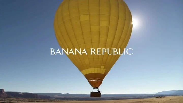A yellow hot air balloon floats in a clear blue sky over a desert landscape with the Banana Republic logo superimposed in white.
