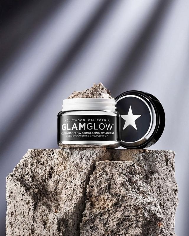 GlamGlow skincare product on textured stone surface against a blurred light and shadow backdrop, showcasing beauty and skincare.