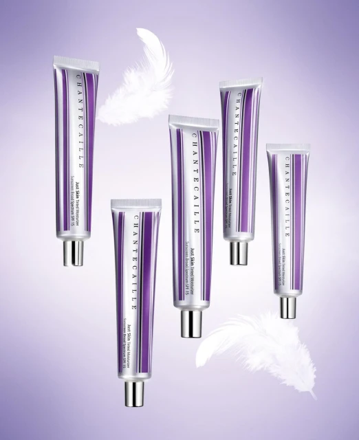 Chantecaille skincare product tubes displayed with white feathers against a soft gradient purple background in a beauty product shot.