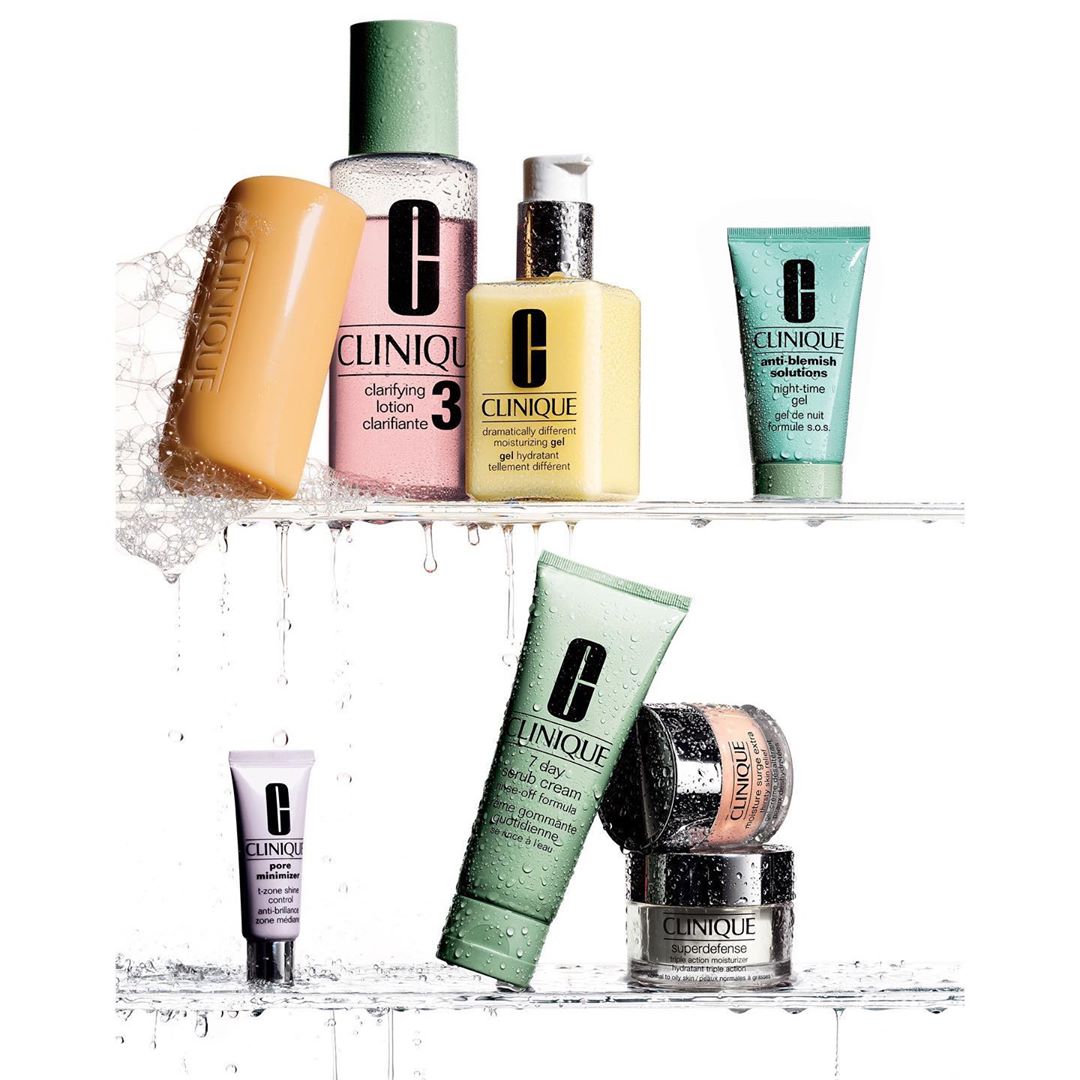 Clinique skincare products arranged on white shelves with water droplets. Products include lotion, soap, cream, and gel in various sizes.