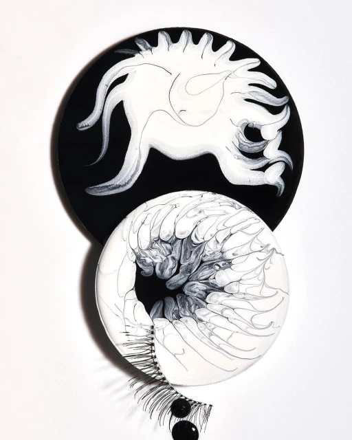 Abstract art featuring black and white circular forms with eyelash accents against a white backdrop. Minimalist aesthetic and design focus.