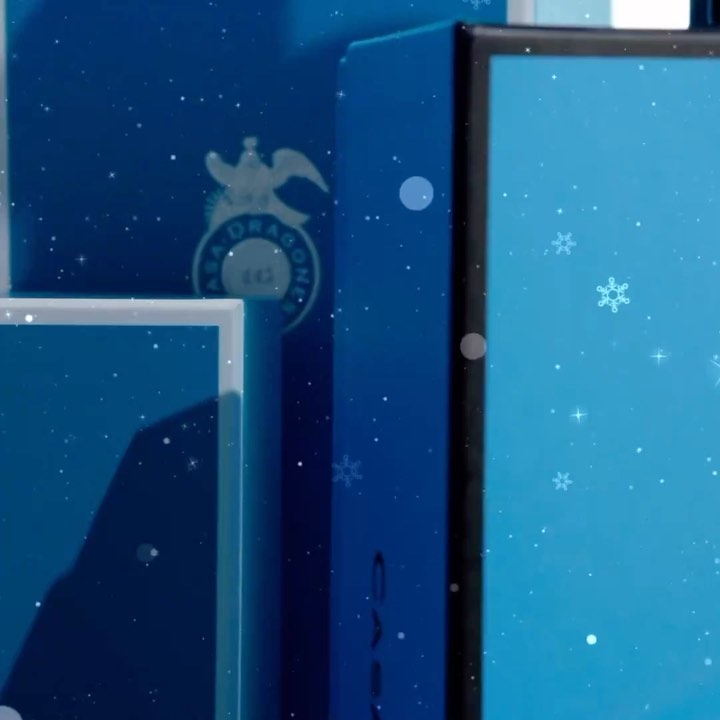 Elegant blue product packaging with a logo and snowflakes, illuminated with a soft light, create a festive mood in a close-up view.