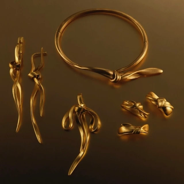 Elegant gold jewelry set featuring a necklace, earrings, and rings, displayed on a dark surface with a studio lighting setup.