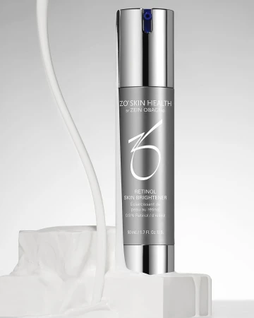 Silver ZO Skin Health Retinol Skin Brightener bottle on white textured block against light grey background. Product shot for beauty industry.
