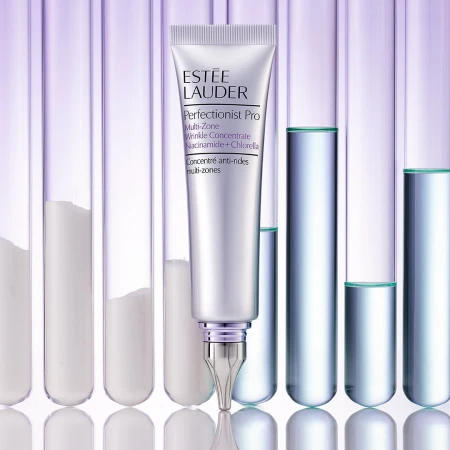 Silver tube of Estee Lauder Perfectionist Pro wrinkle concentrate against a background of glass test tubes with clear and white liquid.
