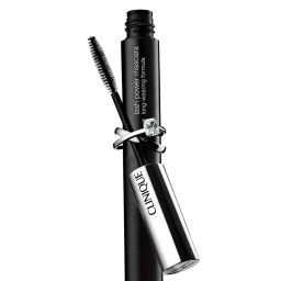 Black mascara tube with a silver ring encircling it and a separate mascara wand resting against it on a plain background