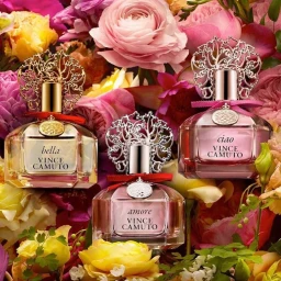 Three Vince Camuto perfume bottles surrounded by colourful fresh pink, yellow, and red roses and florals.
