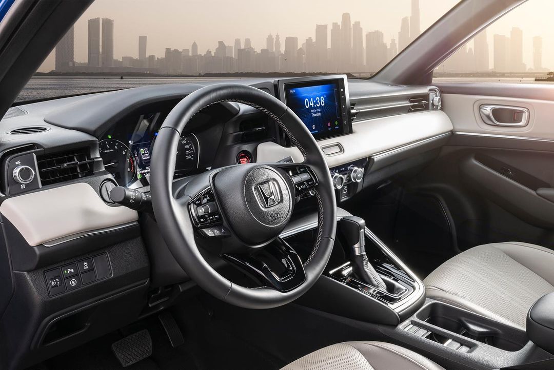 Interior view of a Honda car with a black steering wheel, dashboard display showing time, and a city skyline background.