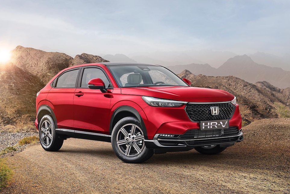 Red Honda HR-V parked on dirt road with mountain backdrop, daytime, showcasing automotive design and outdoor adventure appeal.
