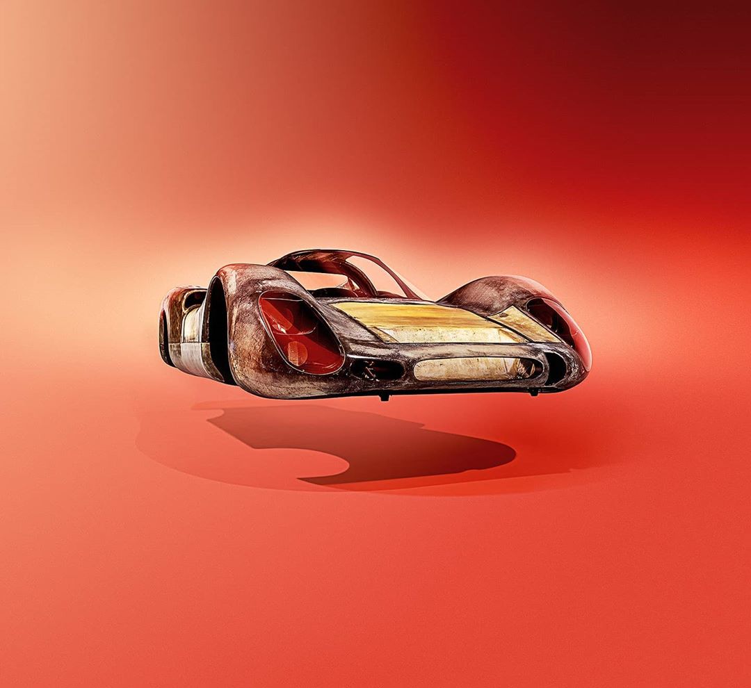 Vintage race car model on an orange gradient background, showing weathered texture and aerodynamic design.