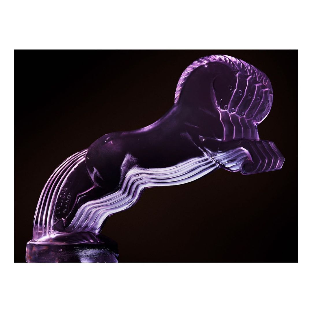 Crystal horse sculpture against a dark background. The piece has a glossy, translucent appearance with a smooth, layered design.