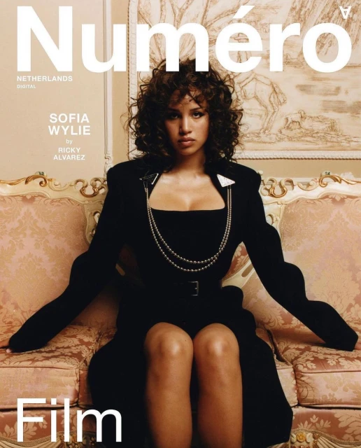 Magazine cover featuring Sofia Wylie sitting on a pink couch, wearing a black dress and silver necklace, in an indoor setting.