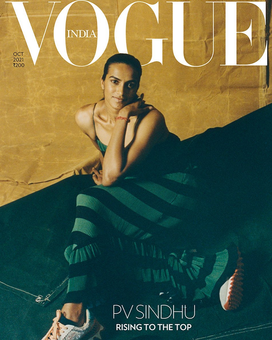 Vogue India magazine cover featuring a woman in a green striped outfit reclining against a gold backdrop and wearing sneakers.