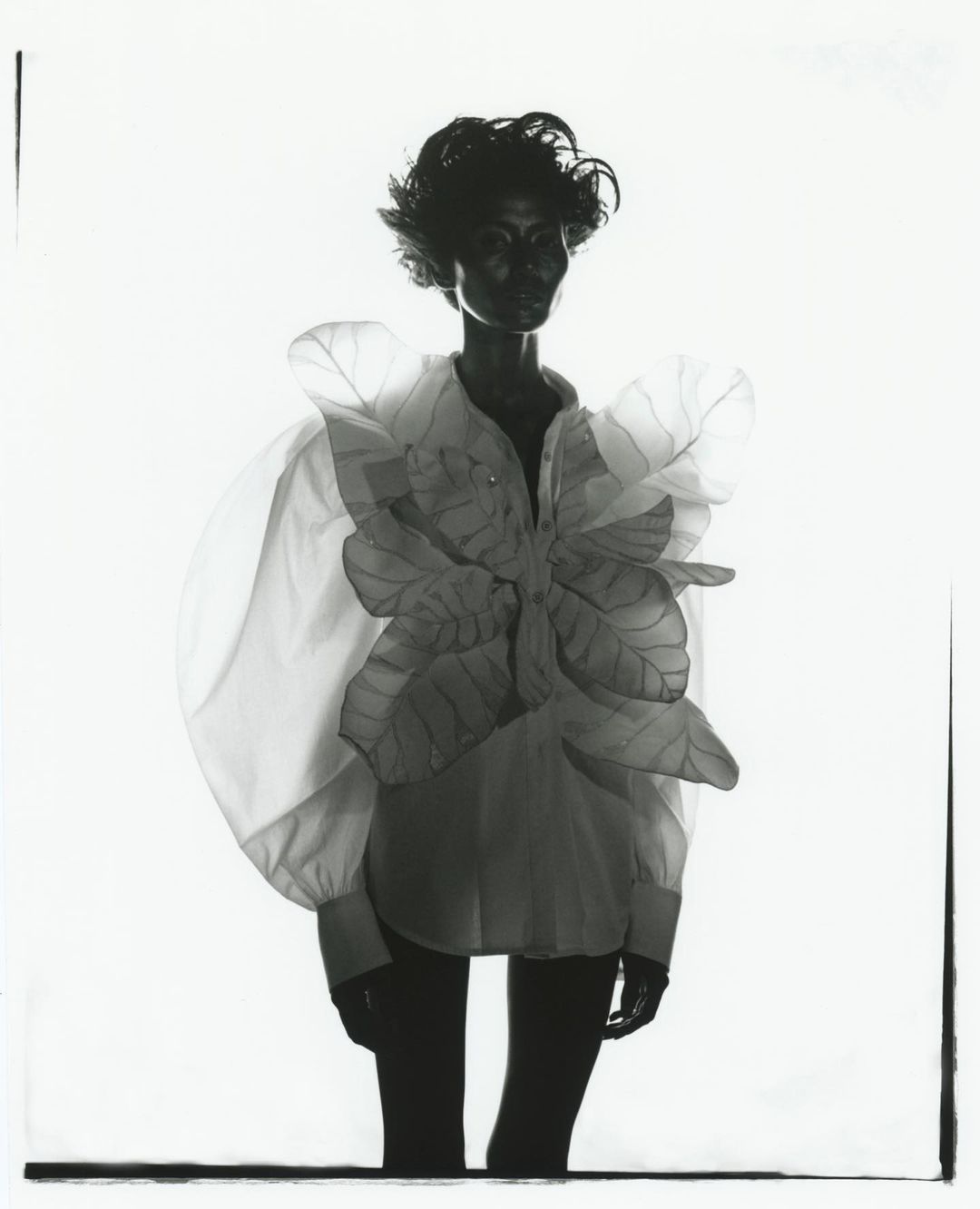Black and white portrait of a model in a white shirt with sculptural leaf appliques by photographer Rid Burman
