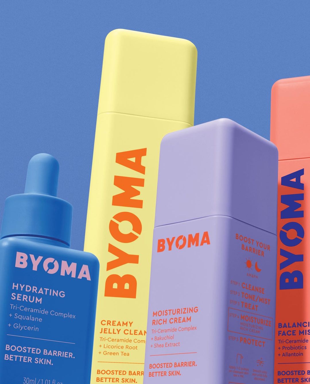 Four colorful skincare bottles from BYOMA are displayed against a light blue background. Product labels are visible with product details.