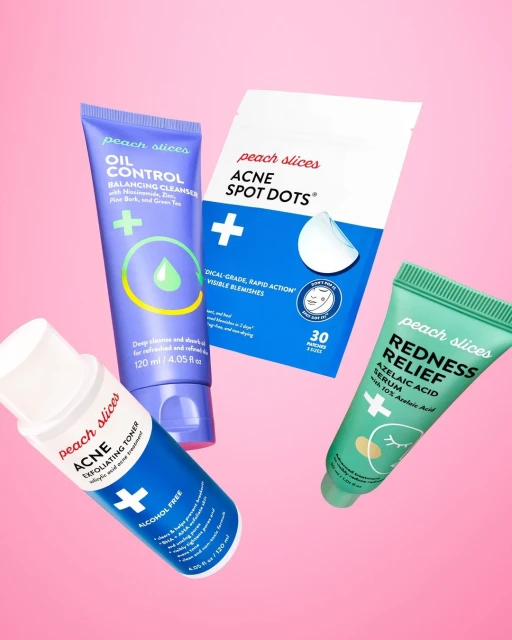 Peach Slices acne skincare products in blue, purple, and green tubes and packaging against a pink backdrop.