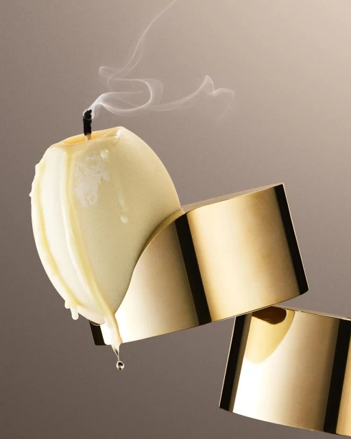 Elegant still life of an ivory candle with smoke on a gold stand against a gradient neutral background, showcasing minimalist home decor.