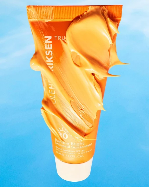 Ole Henriksen Banana Bright Mineral Sunscreen tube with a swatch of cream on a blue background. Beauty and skincare concept.