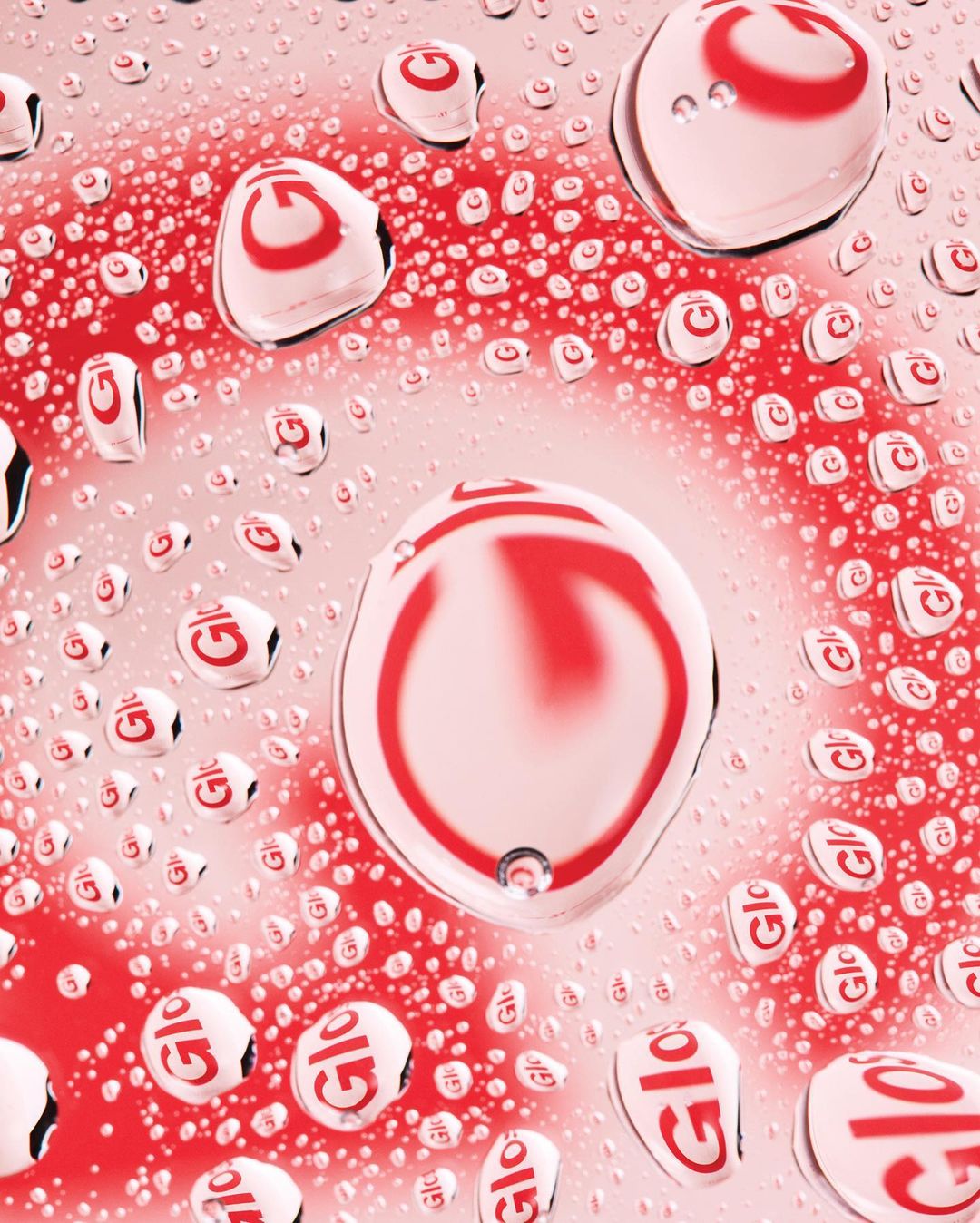 Water droplets on a surface with a red and white circular pattern reflected in the droplets, creating an abstract design.