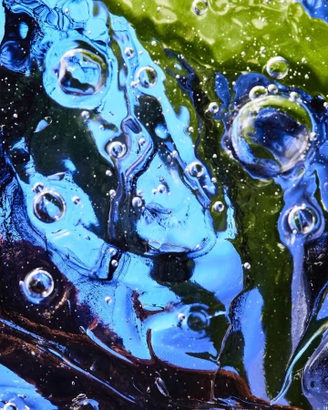 Macro shot of abstract translucent blue and green liquid or gel with bubbles, creating an otherworldly and textured effect.