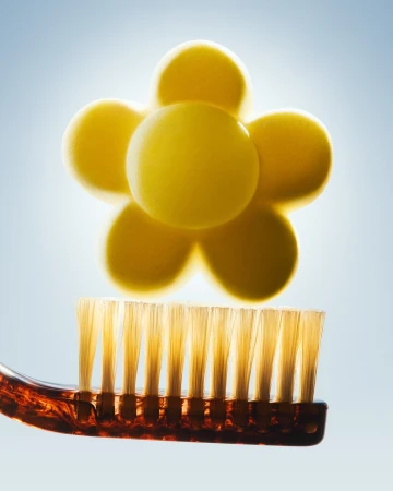 Toothbrush with a yellow molecular structure above it, creating a clean and bright visual for oral hygiene and dental health.