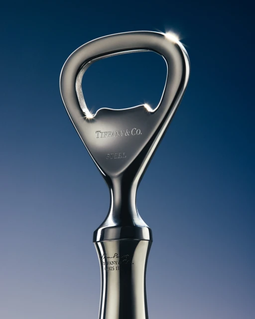 Shiny stainless steel bottle opener with the Tiffany & Co. logo on a blue background. Ideal for barware, gifts, and home décor.