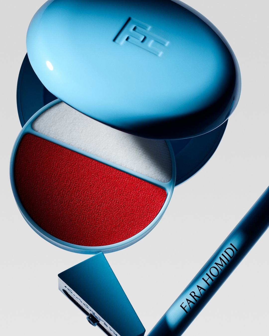 Close-up product shot of a light blue compact with red and white powder, along with a blue handled razor and makeup pencil.