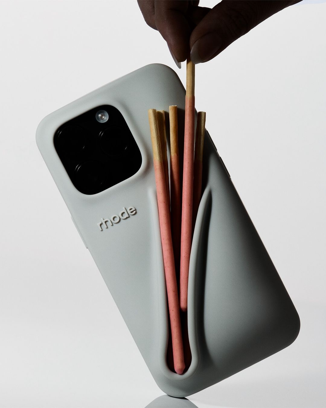Grey cellphone case with the word 'rhode' and multiple candy sticks in a light studio setting. Modern, clean design is highlighted.