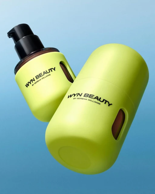 Two Wyn Beauty by Serena Williams products in chartreuse yellow are displayed against a blue gradient background in a product shot.