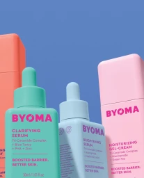 Colorful Byoma skincare bottles including clarifying serum and moisturizing gel cream against a blue background