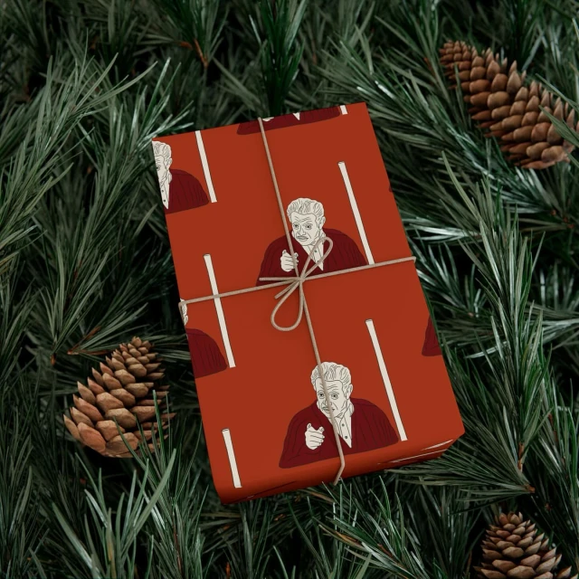 Wrapped gift in orange paper featuring a portrait with pine branches and pine cones in the background. Christmas holiday theme.