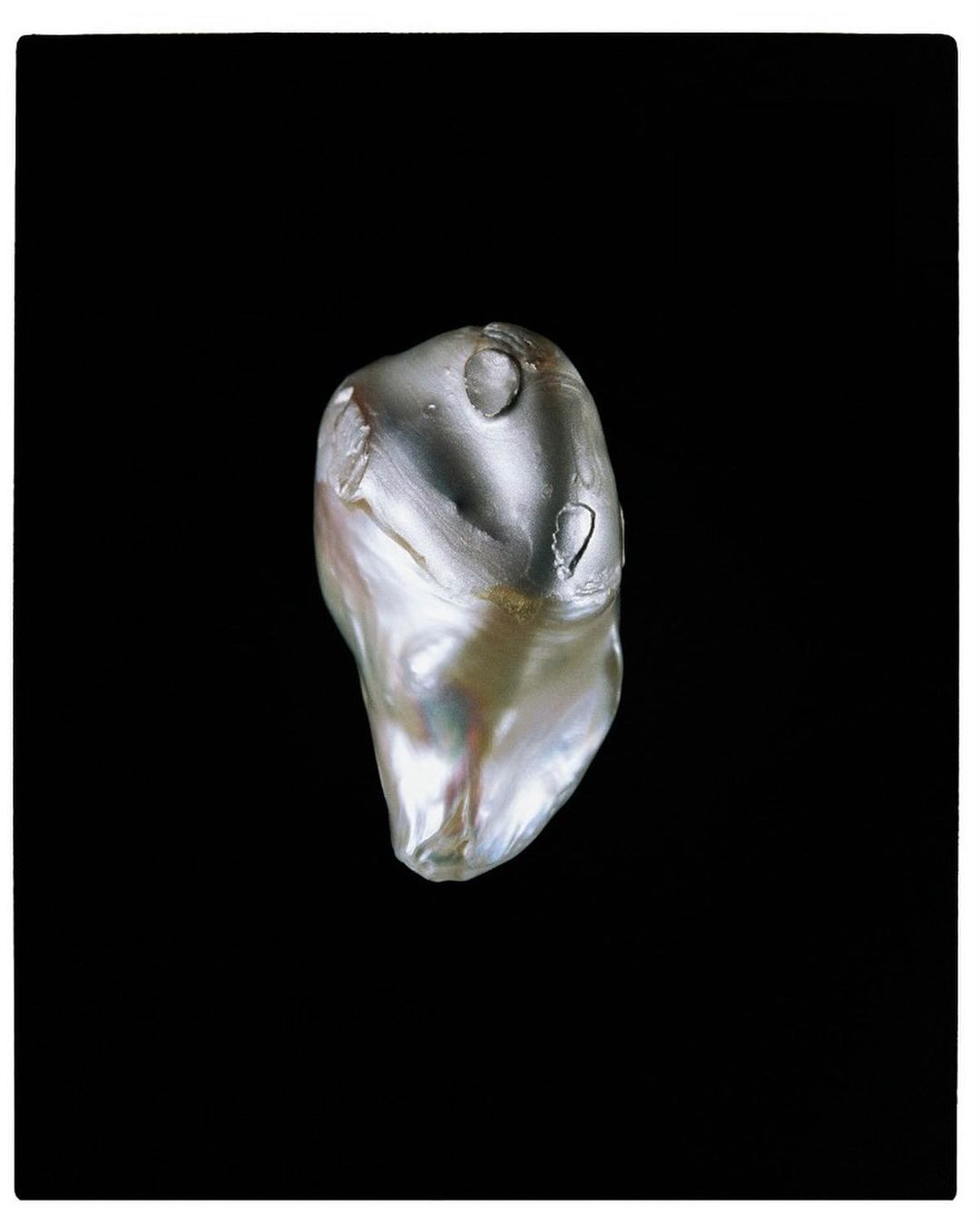 Close-up studio shot of a baroque pearl with iridescent coloring set against a plain black background for jewellery concept.