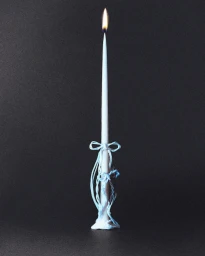 A lit white taper candle wrapped in blue string bows standing against a dark grey textured background.