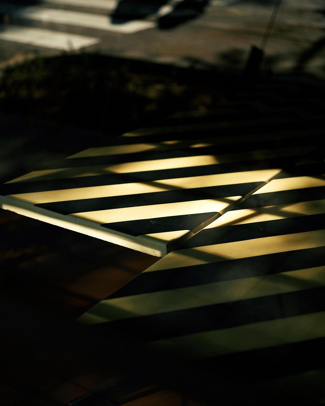 Abstract shot of zebra-striped cafe table with light streaks and crosswalk in background, creating a geometric, high-contrast image.