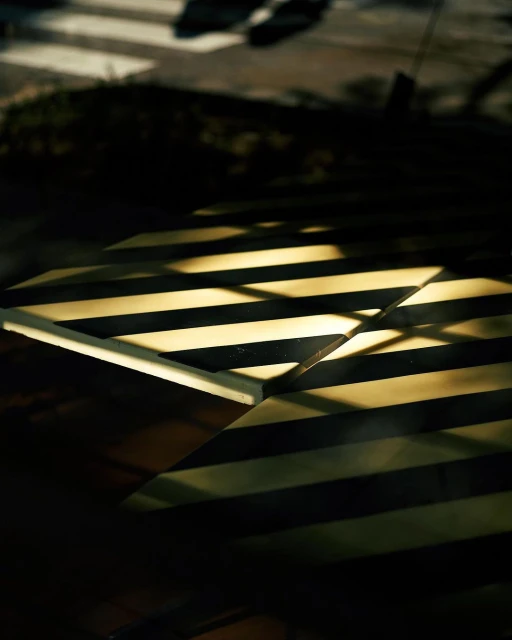 Abstract shot of zebra-striped cafe table with light streaks and crosswalk in background, creating a geometric, high-contrast image.