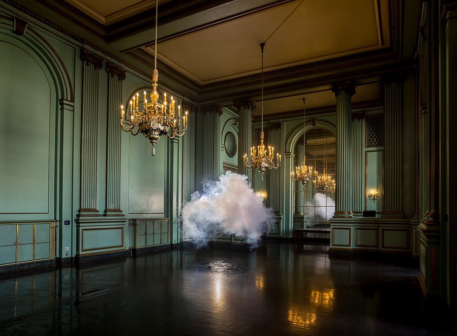Ornate ballroom interior with chandeliers and a cloud of vapor or smoke effect on the polished wood floor creates a surreal atmosphere.